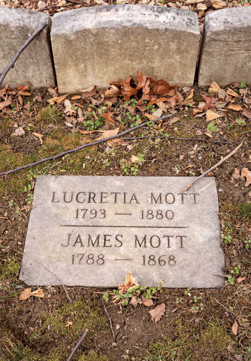 A burial marker for Lucretia and James Mott on the ground in a cemetery.
