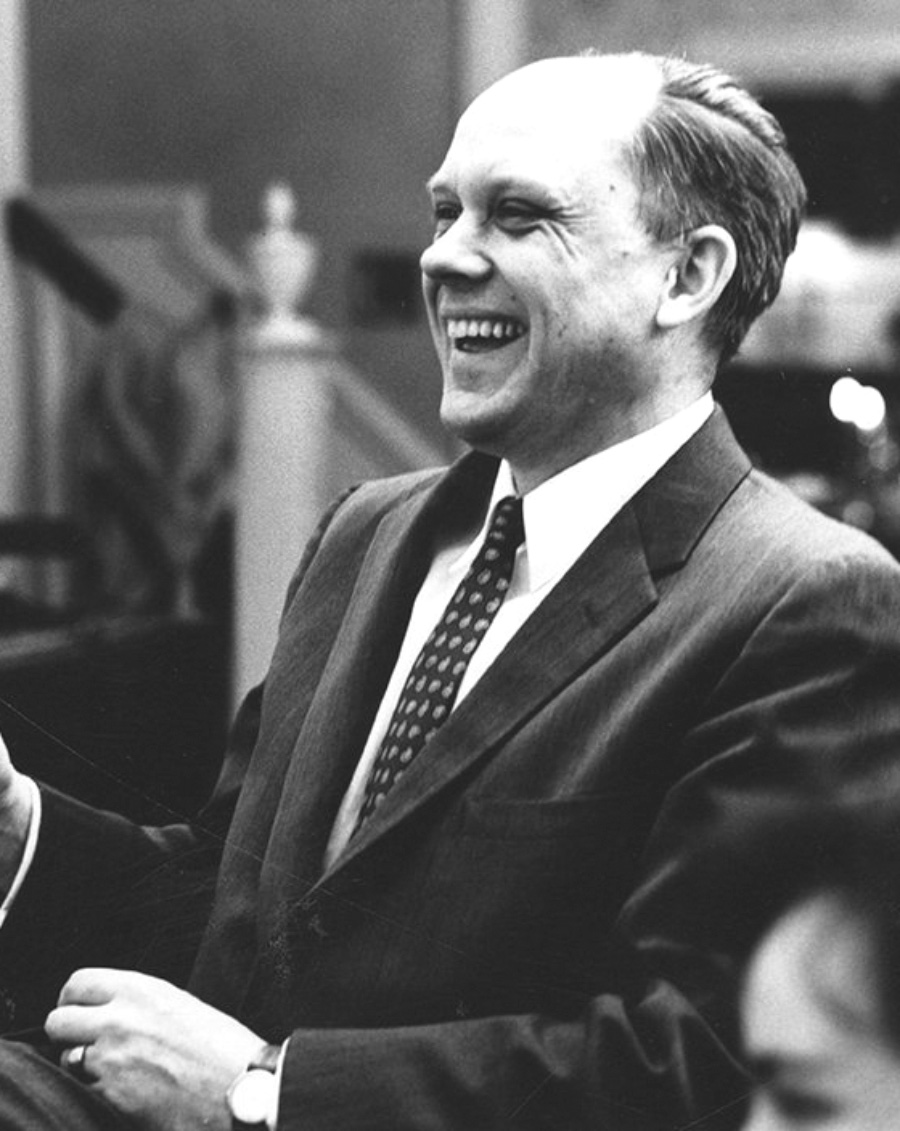Black-and-white photo of P. Linwood Urban, laughing and wearing a suit