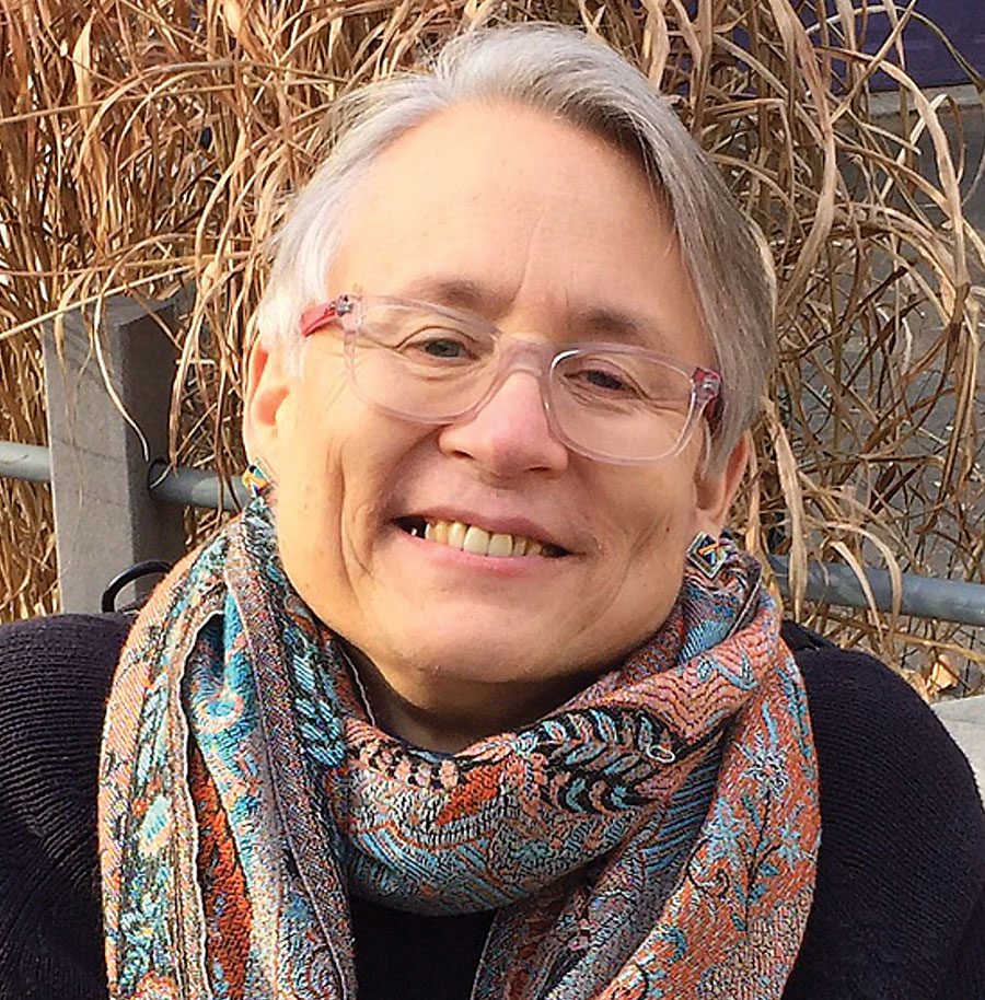 Christina Crosby, smiling and wearing a paisley scarf and glasses