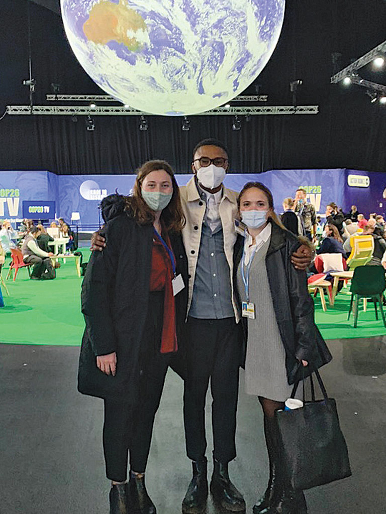 Three masked students huddled together with a large image of Earth in the background