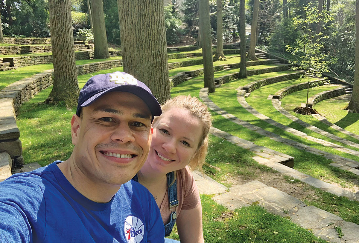 Jorge Aguilar and Caitlin Proper smiling for a selfie in the grass-covered Scott Outdoor Amphitheater
