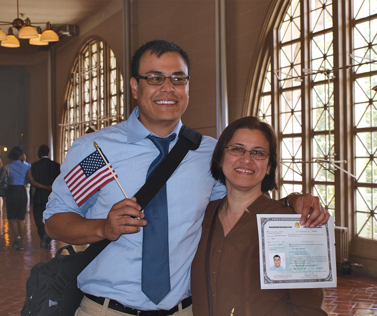 Jorge Aguilar holding a small American flag and his citizenship papers with his arm around his mother, Denia Ching