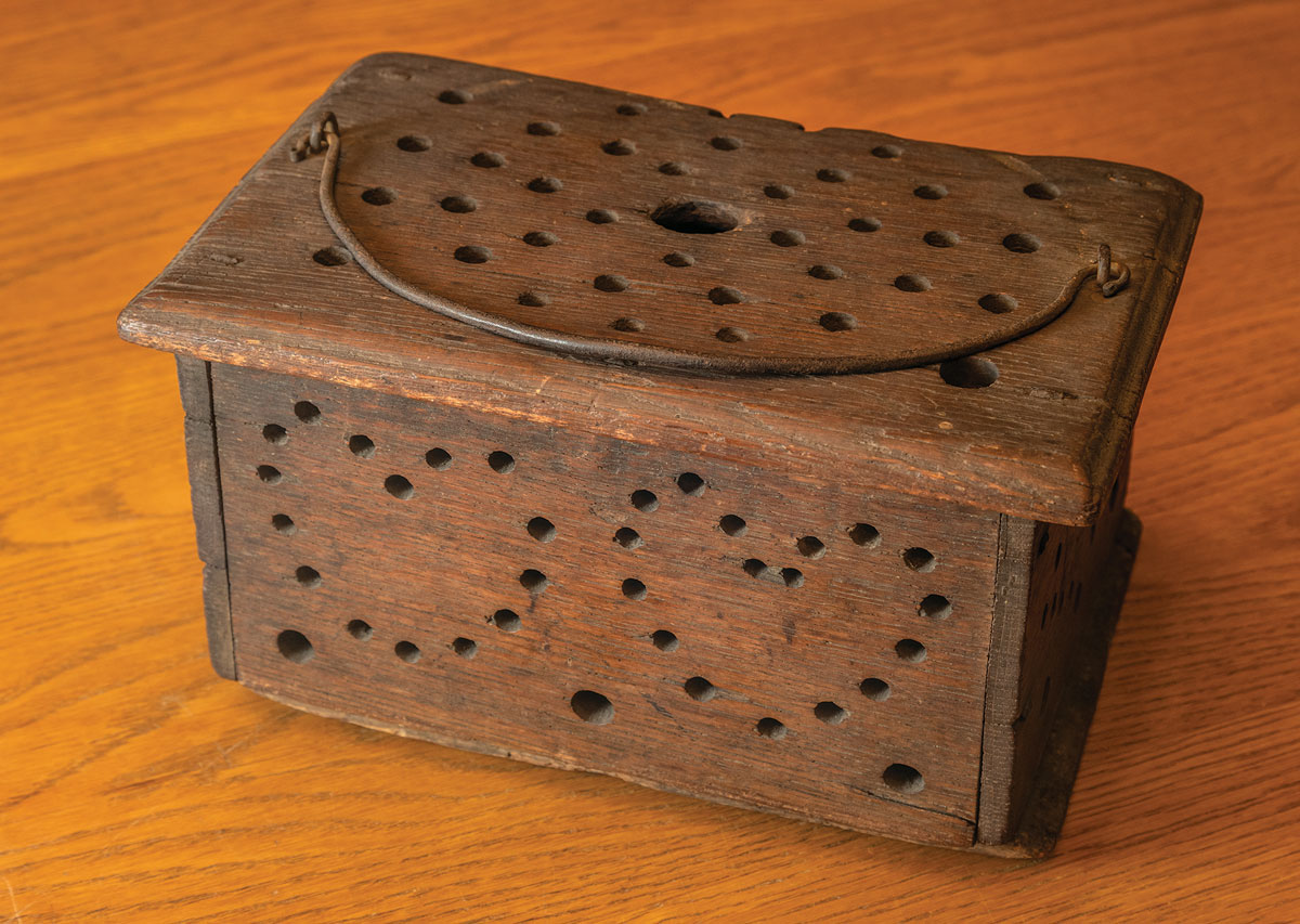 A wooden foot warmer with holes on one side forming the shape of two hearts