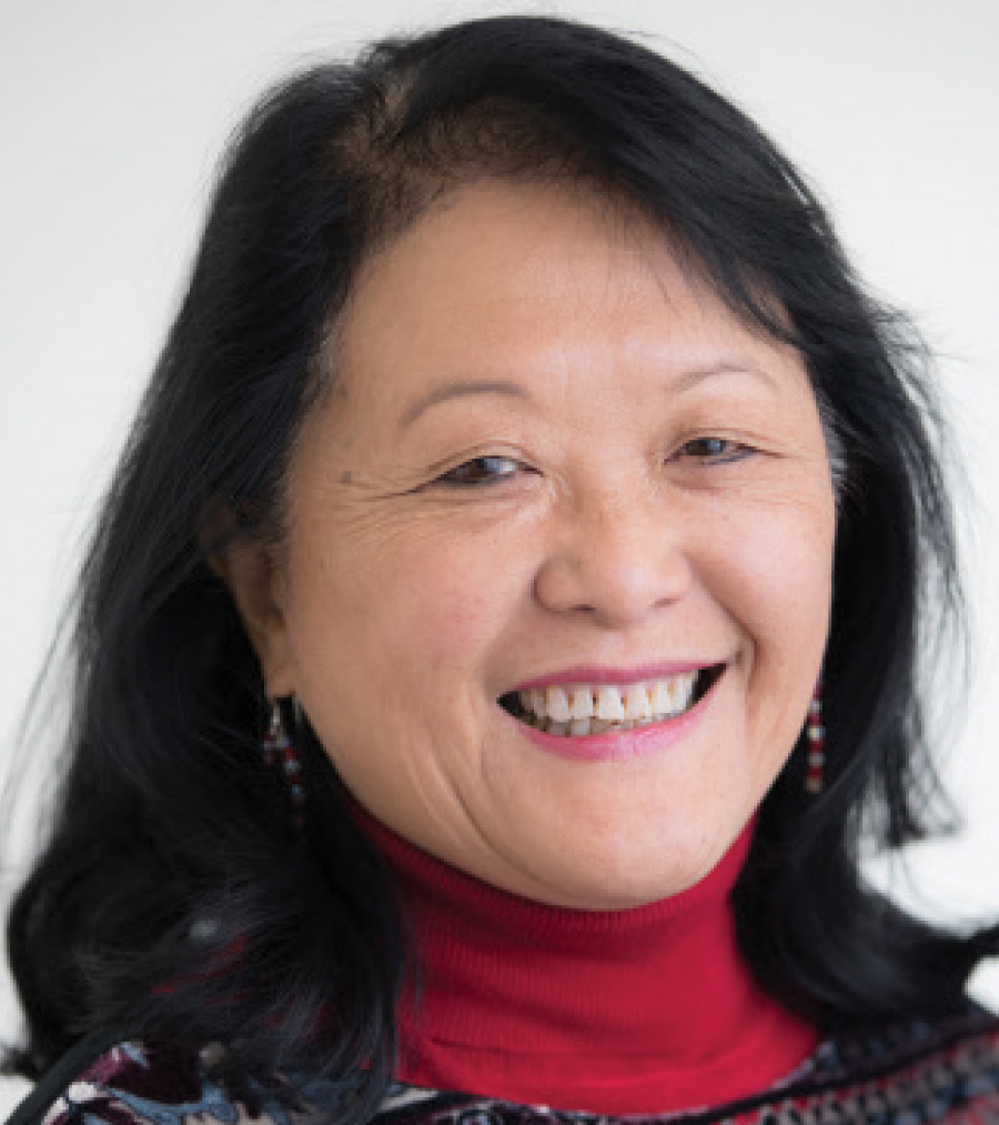 A woman with black hair and red turtle neck smiles.