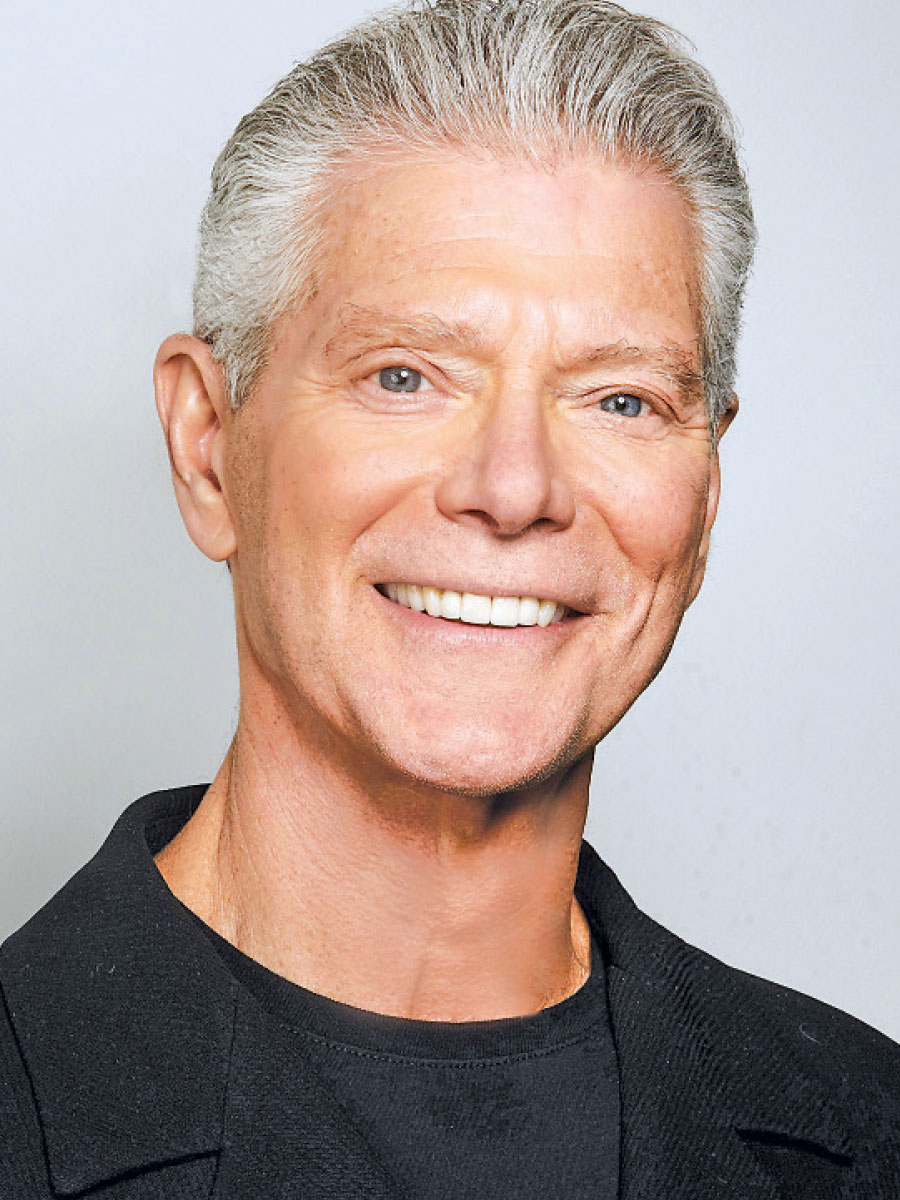 A smiling older man with gray hair and a black t shirt.
