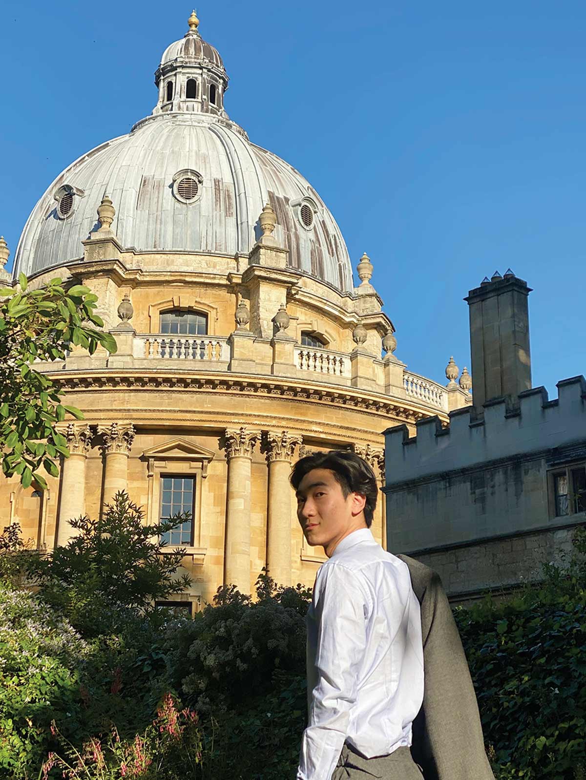 Yifan Ping stands in front of an old building on a sunny day.