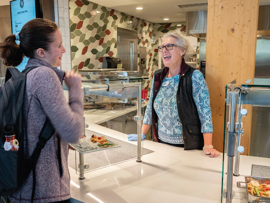 A student stops to chat with one of the Dining Services staff members at a serving station.