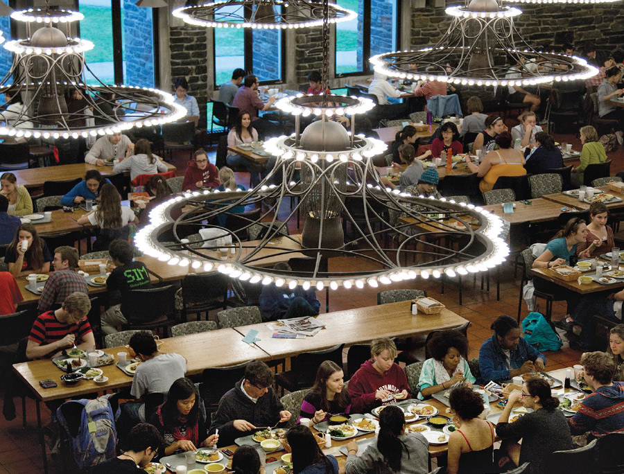 Students enjoy dinner under chandeliers.