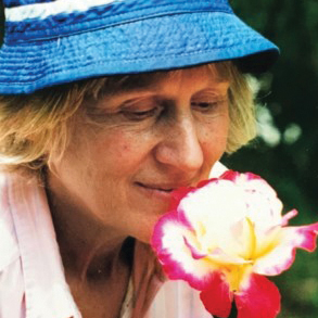 Nancy Grove Malone '55 wears a blue hat and smells a flower.
