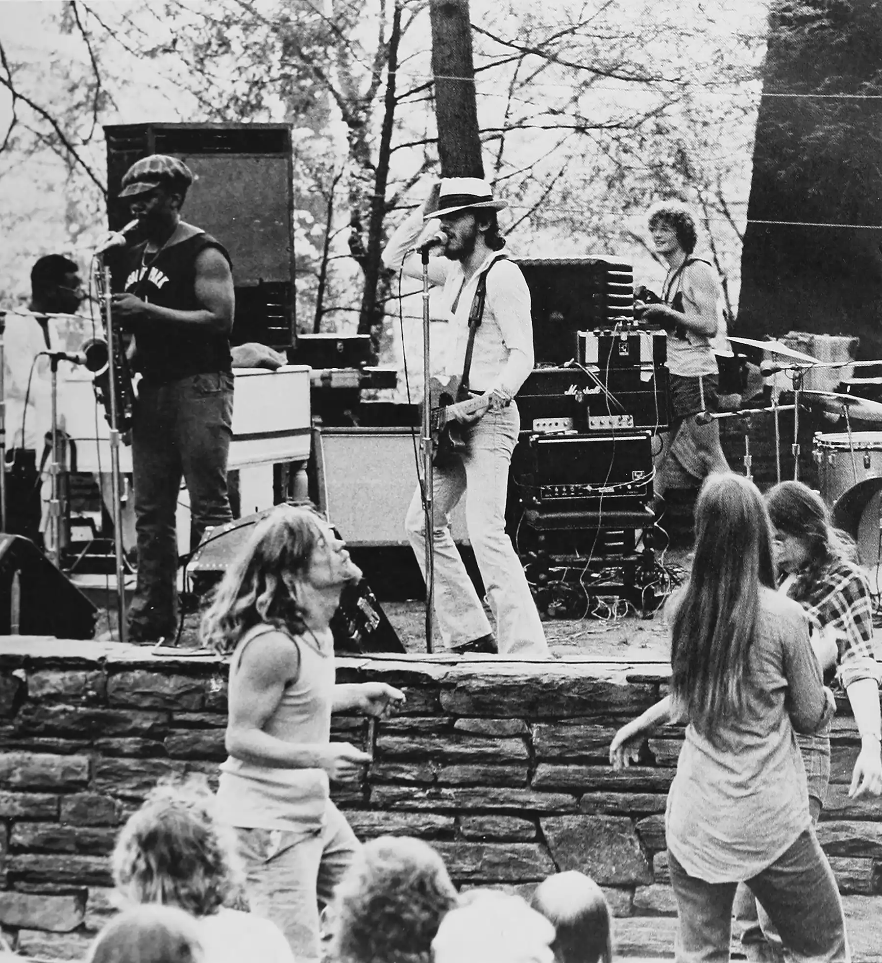 Bruce Springsteen center stage in a black and white photo, Black and white image of Bruce Springsteen and the E-Street Band performing in the Scott Outdoor Amphitheater in 1974. Students dance in front of the stage.