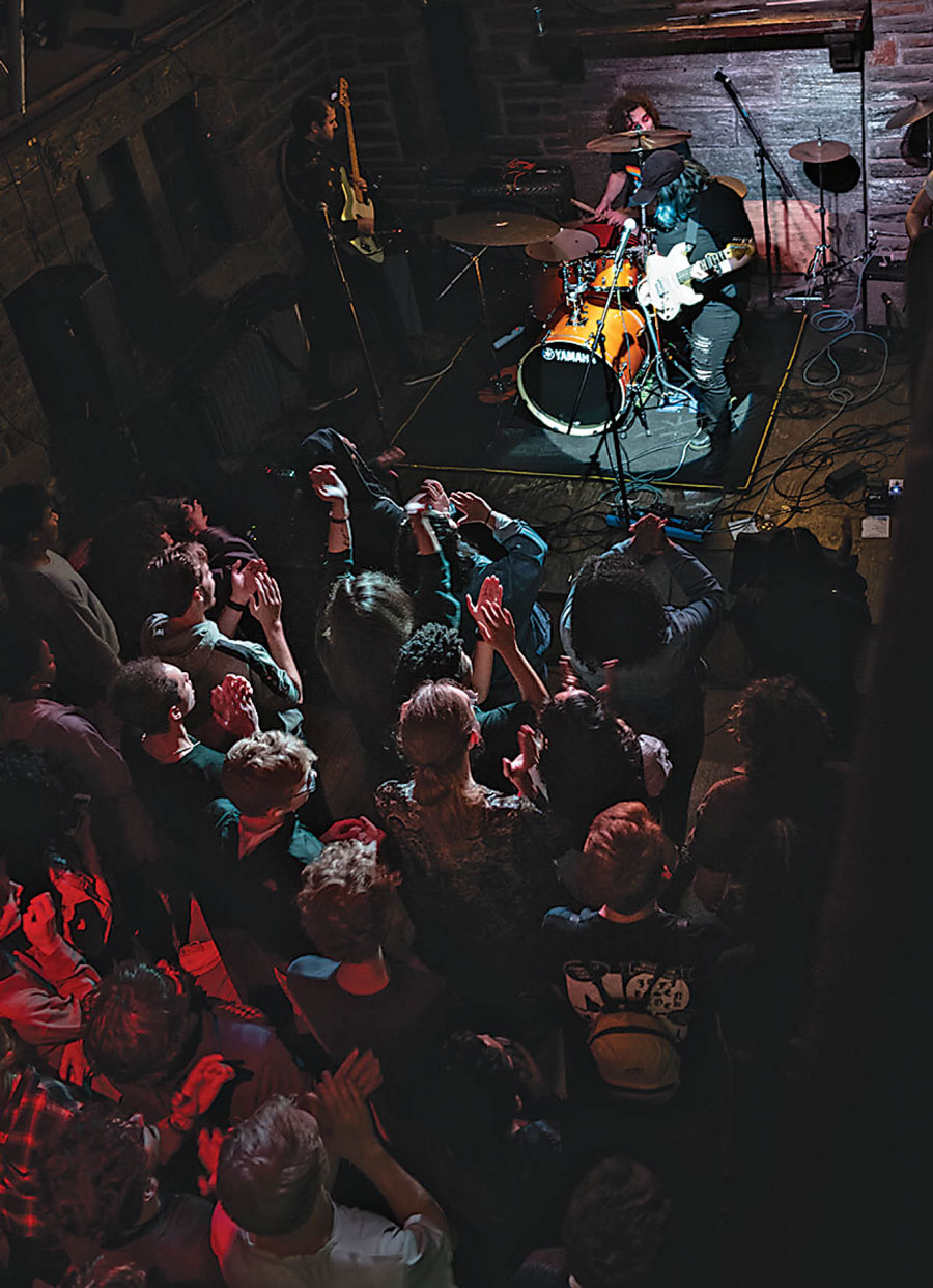 Overhead shot of concert-goers. Drummer and guitarist can be seen on stage.