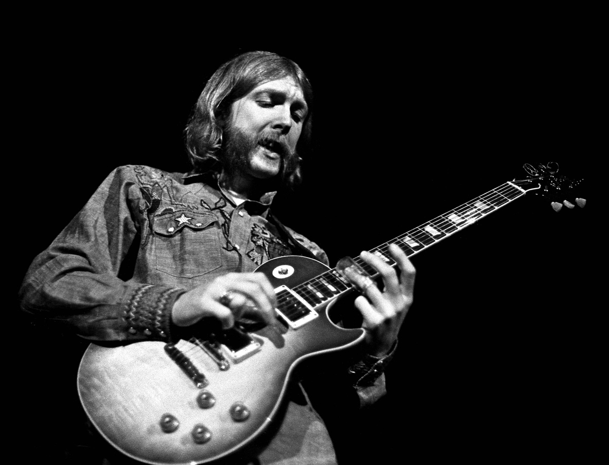 Black and white photo of Duane Allman playing guitar