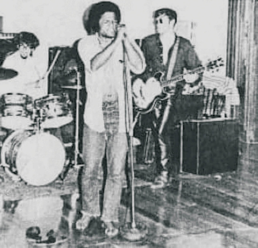 Black and white image of Phaedra performing. Singer, drummer, and guitarist can be seen on stage.