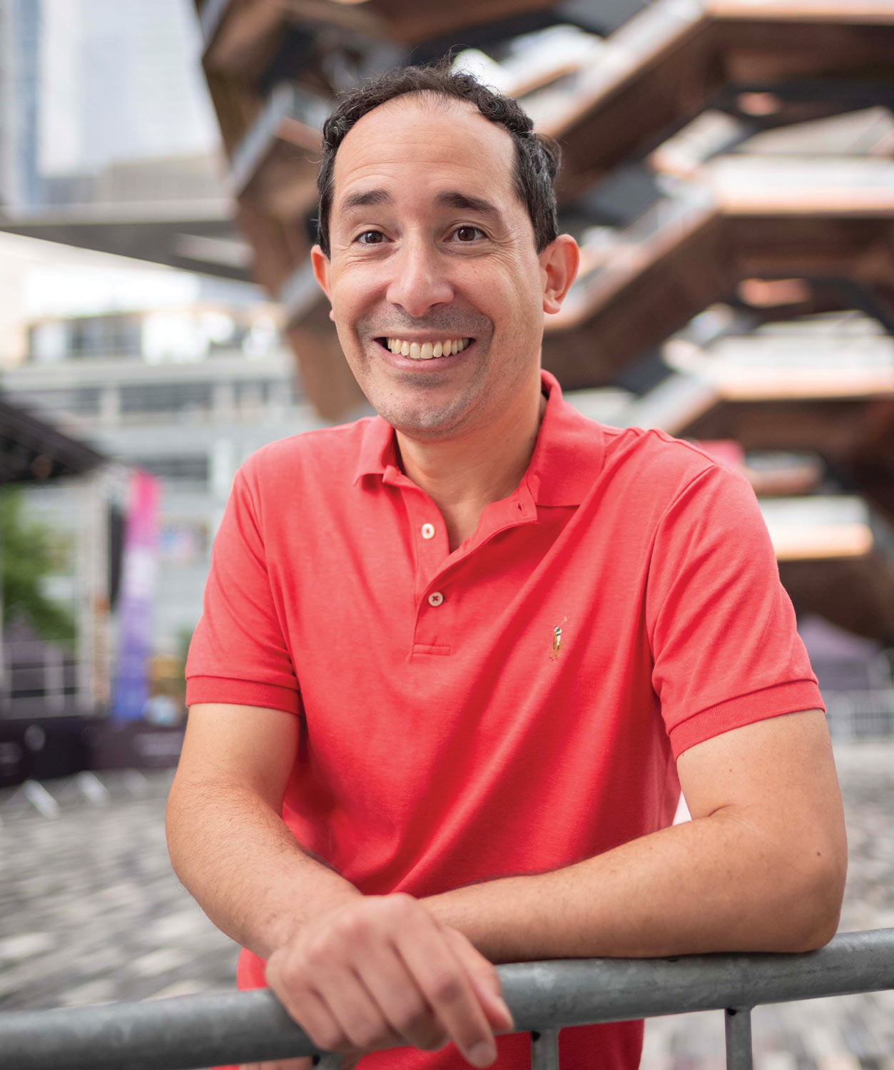 Piñeiro smiles at the camera, wearing a bright coral-colored polo shirt.
