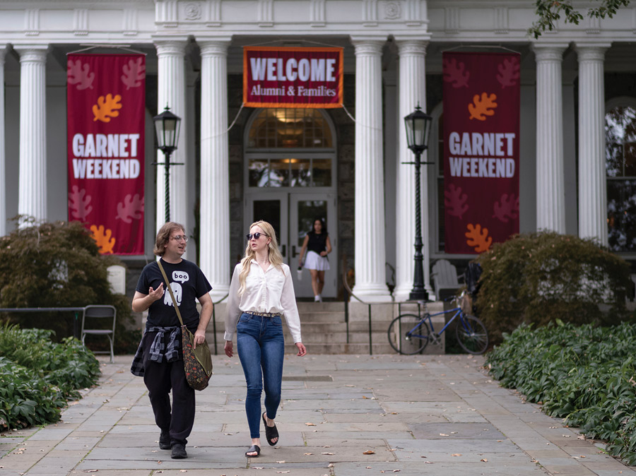 Students and alums walking down Magill Walk from Parrish Hall with Garnet Weekend banners hanging behind them.