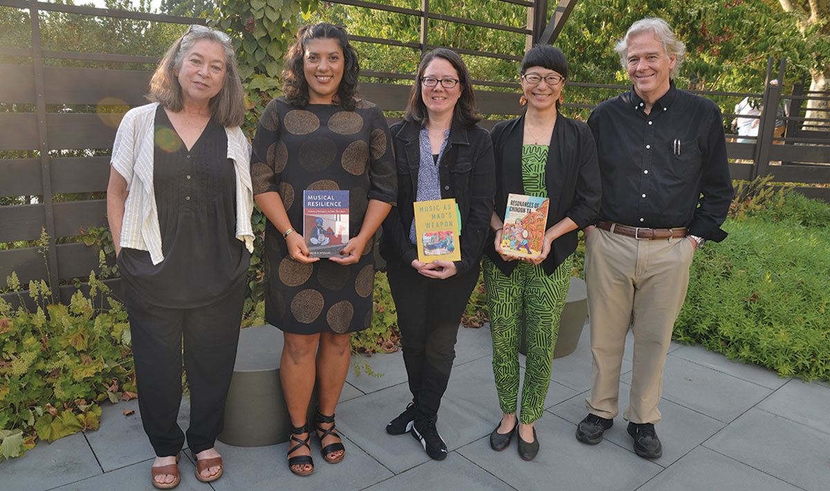 Panelists stand outside holding their books.