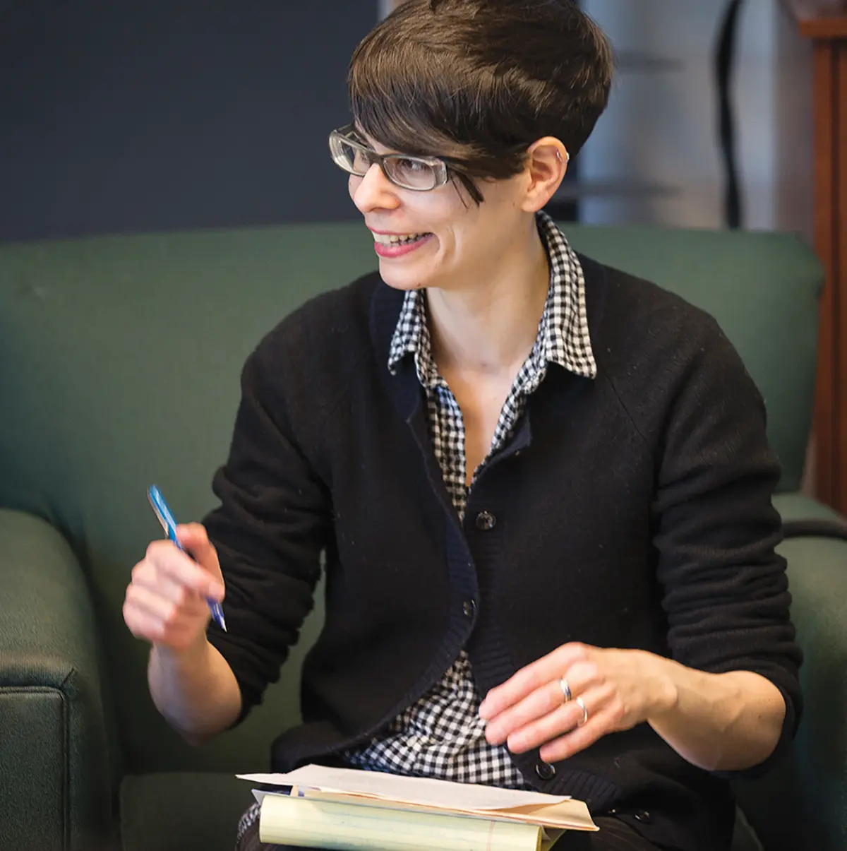 Rachel Buurma, holding a pen and looking to the left, with a stack of teaching materials in front of her.