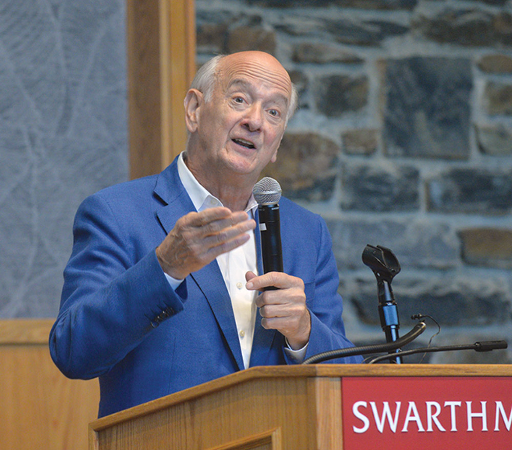 Gil Kemp '72 stands behind a podium and speaks into a microphone.