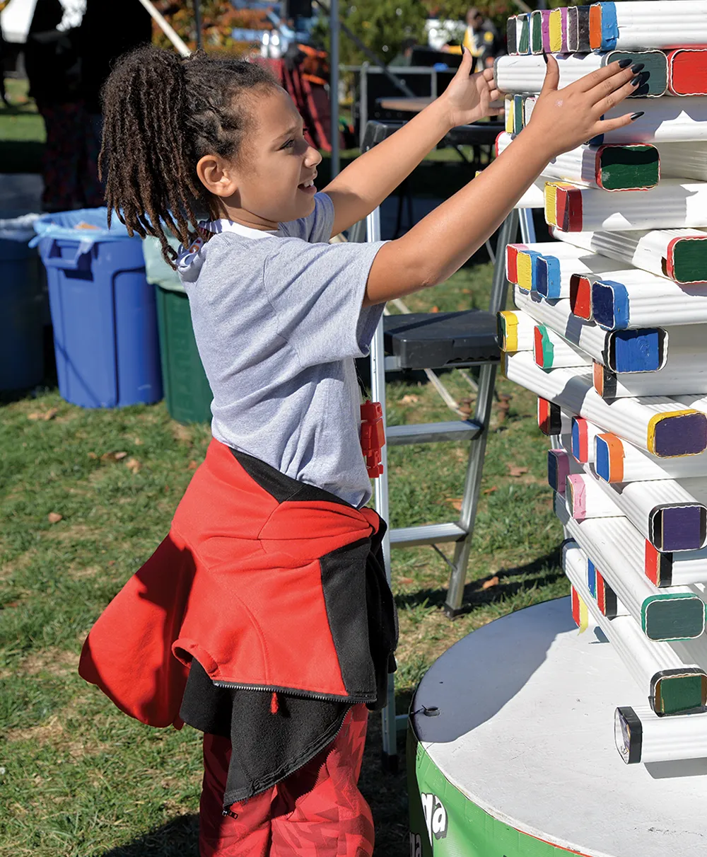 Child tries to remove a block from a giant game of Jenga.