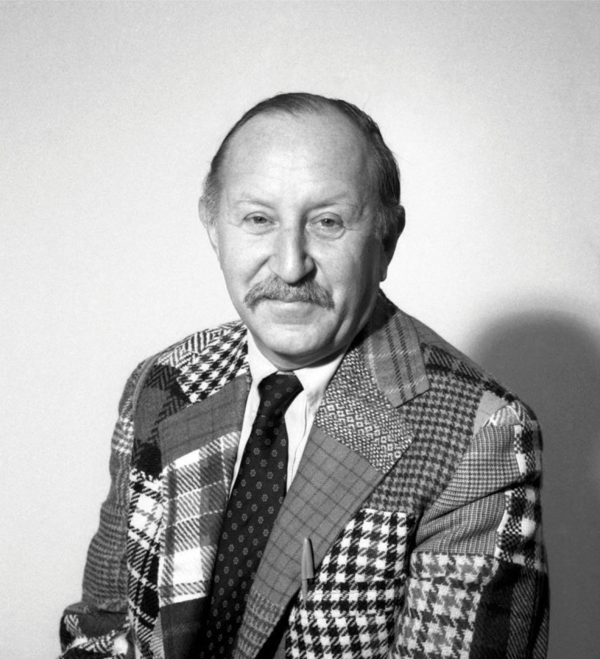 Black and white shot of Heywood Hale "Woodie" Broun. He wears a sports coat of many different fabrics and patterns.