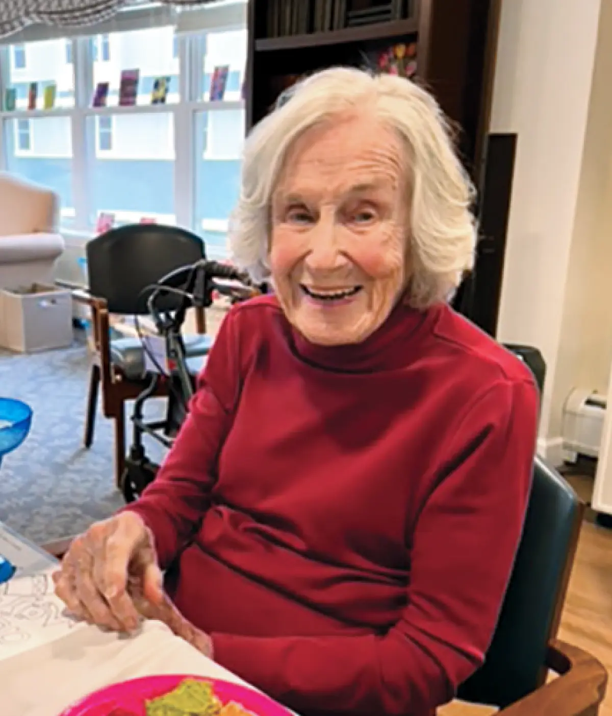 Betty Murch Livingston smiles at the camera, wearing a red long-sleeved shirt.