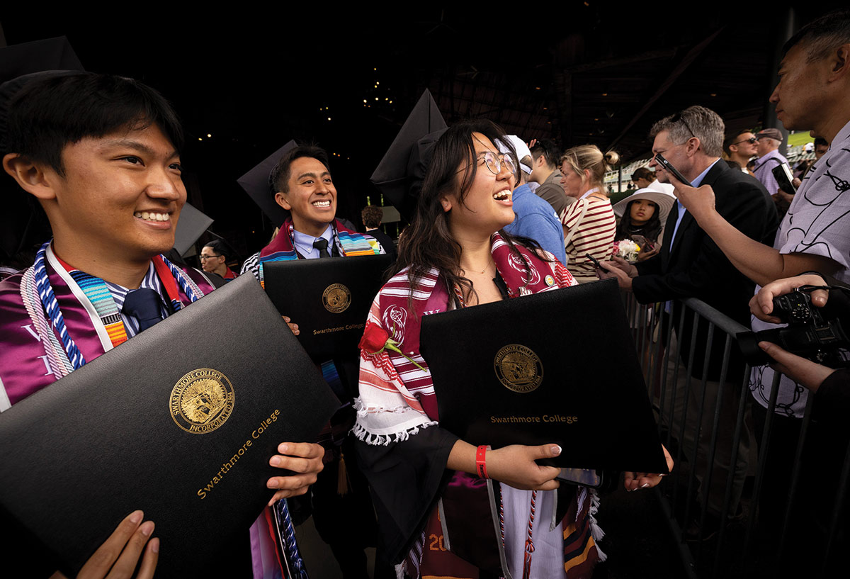 Students smile while holding their diplomas.