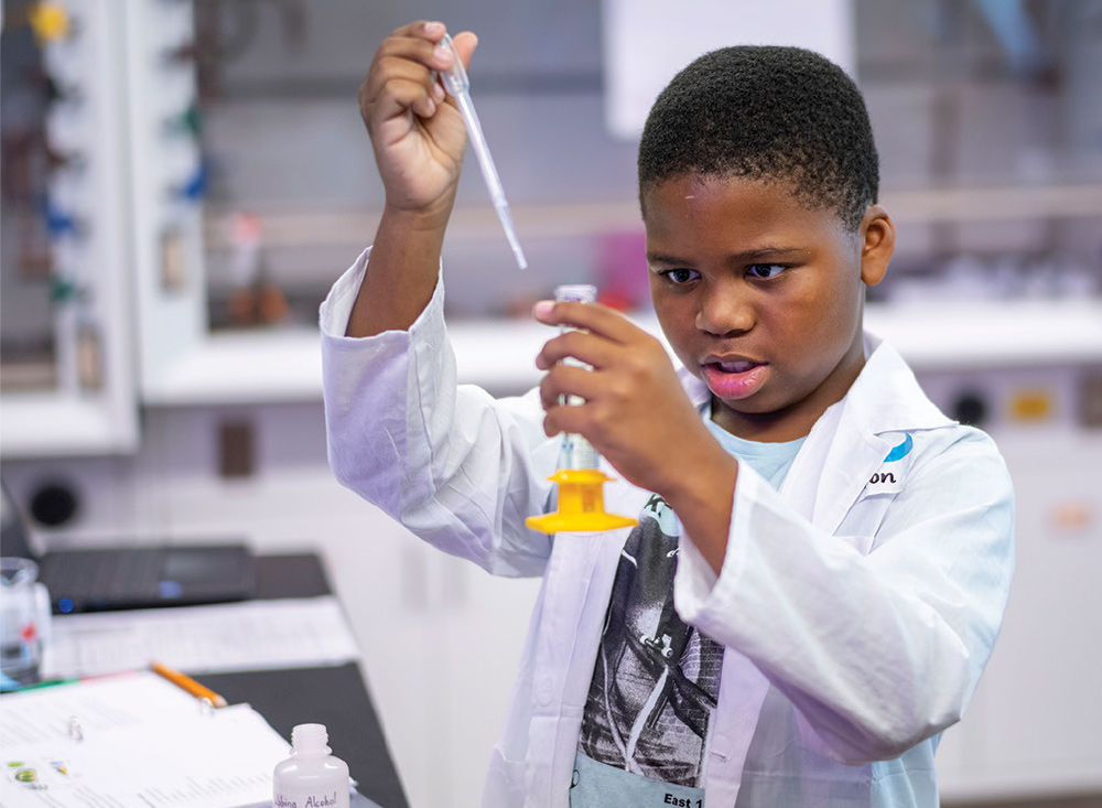 Brion Dorsey moves liquid from a pipette into a beaker in a lab.