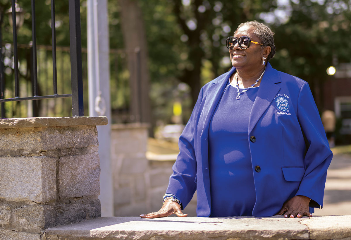Rosemarie Ewing-James stands outside in sunglasses and a blue top.