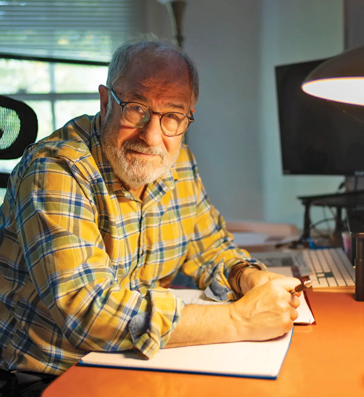 Ted Gup sits at his desk in low light