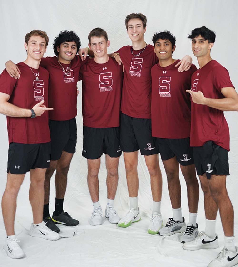 Men's tennis team poses and smiles.