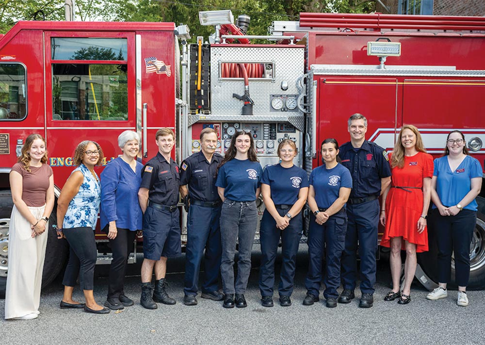 Swarthmore students and firefighters stand in front a red fire truck.