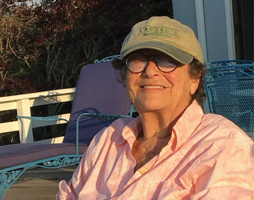 Marge Pearlman Scheuer '48 wearing a pink shirt, glasses, and a green baseball cap