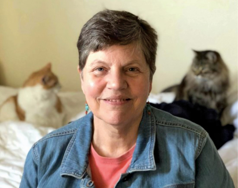 Elizabeth "Betsy" R. Sander '74 sits with her cats behind her.