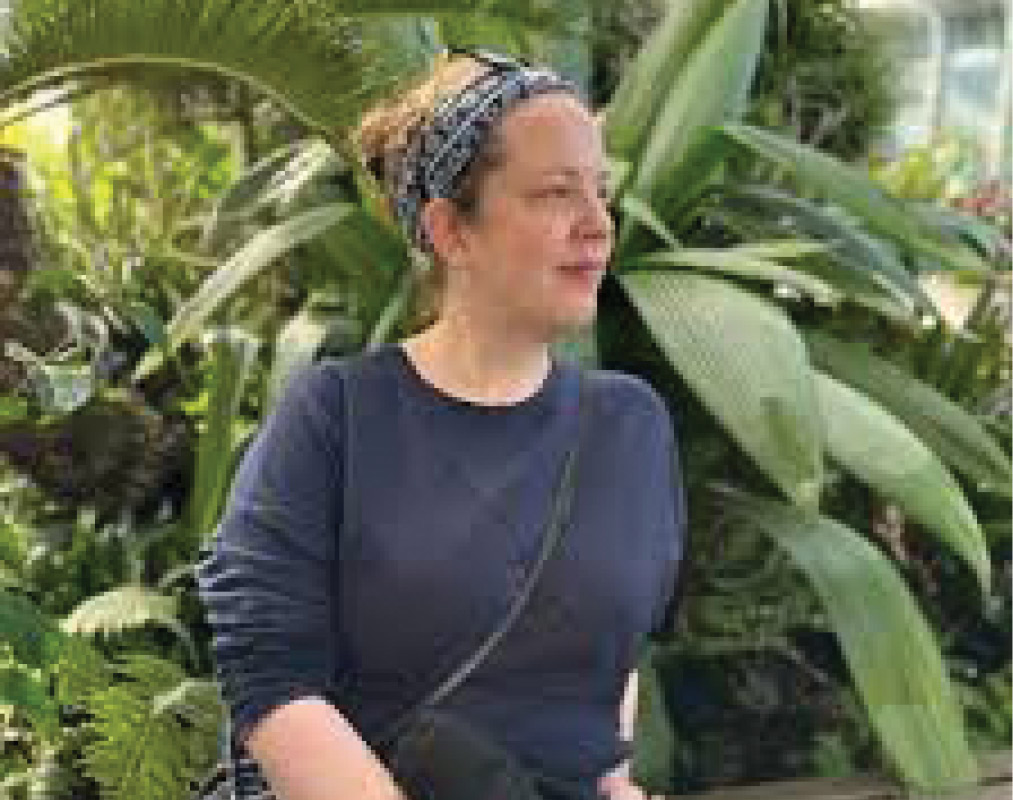Anna Staab '02 stands in front of lush tropical greenery