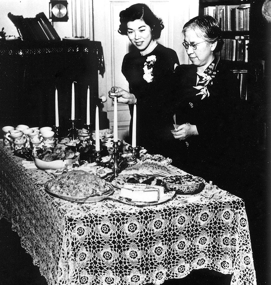 Black and white photo of two women setting a table.